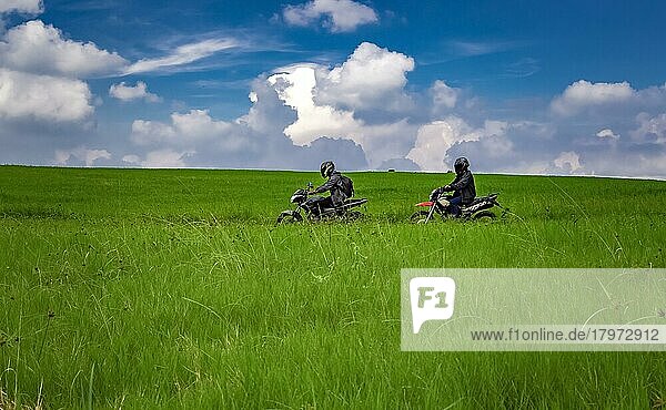 Junger Mann auf seinem Motorrad auf der Fahrt durch die Landschaft mit Kopierraum  Mann fährt Motorrad auf dem Lande