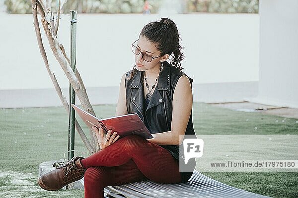 Eine Studentin liest ein Buch  ein städtisches Mädchen sitzt auf einer Bank und liest ein Buch  ein lateinisches Mädchen liest ein Buch im Freien
