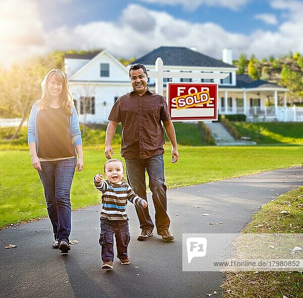 Glückliche gemischtrassige Familie  die vor einem Haus spazieren geht  das zum Verkauf steht