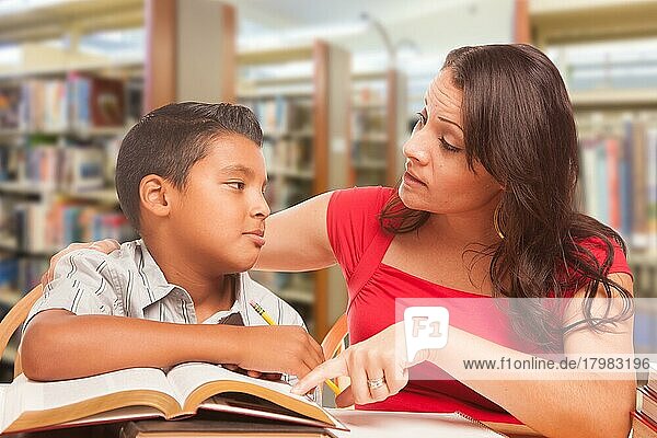 Hispanischer Junge und erwachsene Familie lernen in der Bibliothek