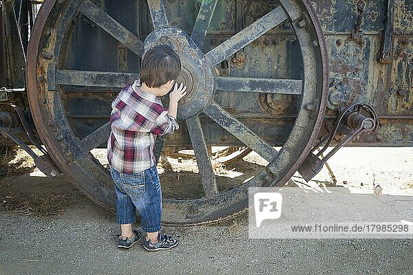 Cute young mixed-race boy having fun near antique machinery outside