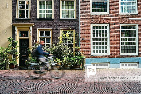 Bewegung unscharf Fahrradfahrer Radfahrer Mann auf Fahrrad sehr beliebtes Transportmittel in den Niederlanden in Straße mit alten Häusern von Delft  Niederlande  Europa