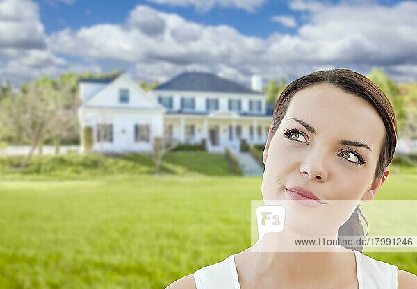 Nachdenkliche hübsche gemischtrassige Frau vor einem Haus  die nach oben und zur Seite schaut