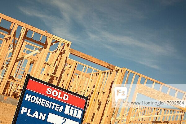 Verkauftes Grundstück Immobilien Schild an neuen Haus Framing Baustelle gegen tiefblauen Himmel