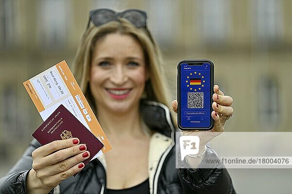 Symbolfoto Impfprivilegien  junge Frau hält Smartphone mit digitalem europäischen Impfpass für deutsche Staatsbürger  mit QR-Code  Reisepass  Boarding Pass  Corona-Krise  Deutschland  Europa