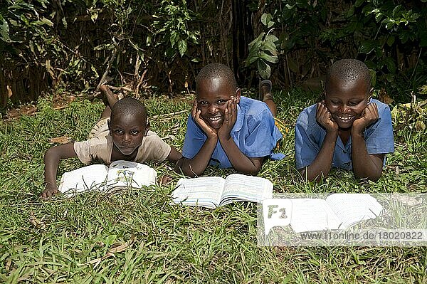 Lächelnde ruandische Kinder beim Lesen von Schulbüchern. Ruanda