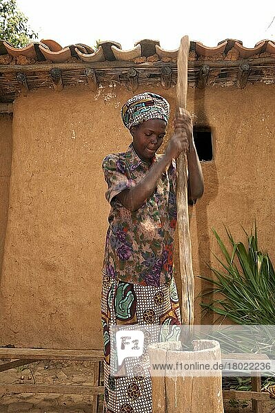 Frau  die Maniok mit einem Stock in einen Holztopf schlägt  um Mehl herzustellen  Ruanda  Afrika