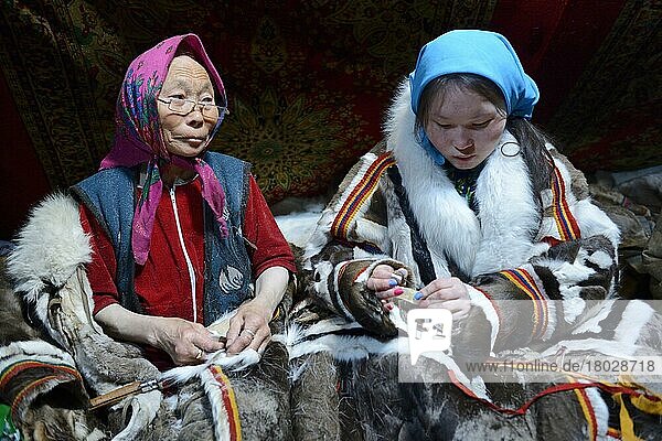 Zwei Generationen von Nenet-Frauen  eine ältere Frau und ein Teegirl  nähen und tragen den traditionellen Mantel aus Rentierfell  Distrikt Yar-Sale  Jamal  Nordwest-Sibirien  Russland  Europa