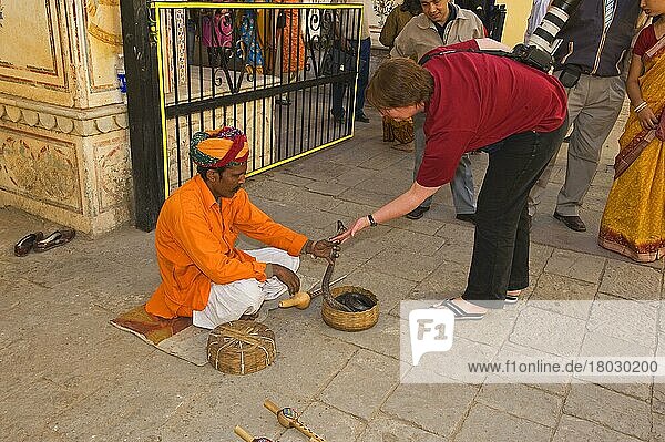 Schlangenbeschwörer mit Kobra  mit Tourist auf der Straße in der Stadt  Jaipur  Rajasthan  Indien  Dezember  Asien