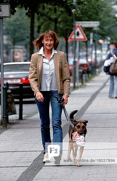 Frau geht mit Mischlingshund einkaufen  geleint  der Leine  freistellbar  Hund trägt Brötchentuete  Nordrhein-Westfalen  Deutschland  Europa