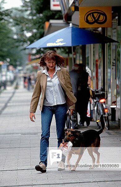 Frau geht mit Mischlingshund einkaufen  geleint  der Leine  Hund trägt Brötchentuete  Nordrhein-Westfalen  Deutschland  Europa