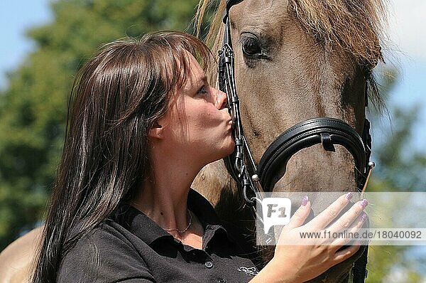 Frau küsst Pferd  Graufalbe  Zaumzeug