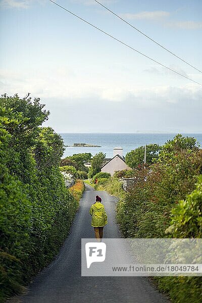 Woman in yellow walking Irish road down to Renvyle beach  Galway  Ireland  Europe
