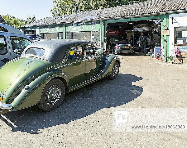 Classic vintage car on forecourt of village car mechanics garage  Somersham  Suffolk  England  UK