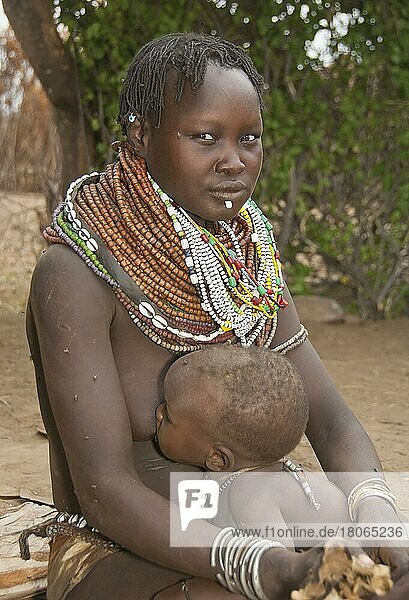 Nyangatom woman with bead necklaces  Bume  Buma  Bumi  breastfeeding  tribe  -tribe  with infant  Omo Valley  Ethiopia  Africa