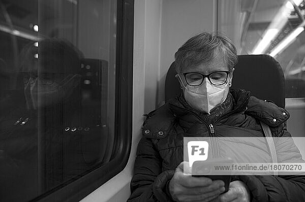 Ältere Frau mit Mundschutzmaske  sitzt in S-Bahn  am Smartphone  Corona-Krise  Stuttgart  Baden-Württemberg  Deutschland  Europa