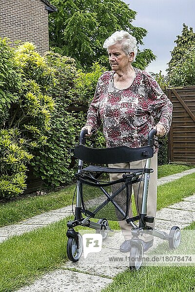 Ältere Frau mit Rollator  Rollator übt das Gehen auf der Auffahrt zu Hause