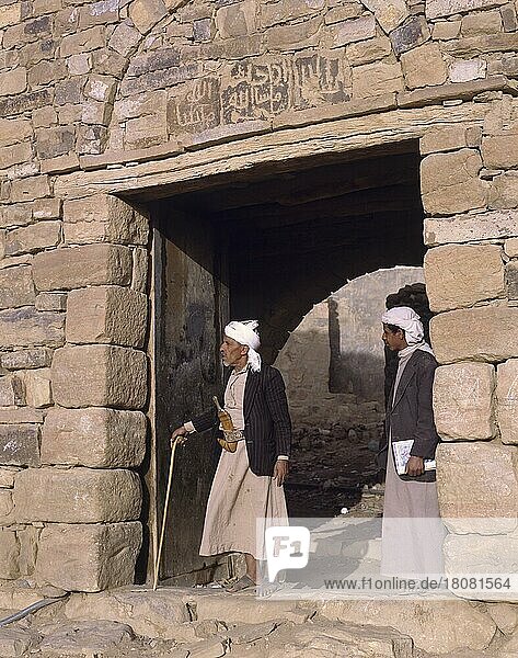 Zwei Personen in traditioneller Kleidung an der Stadtmauer von Thula  Thulla  Jemen  Asien