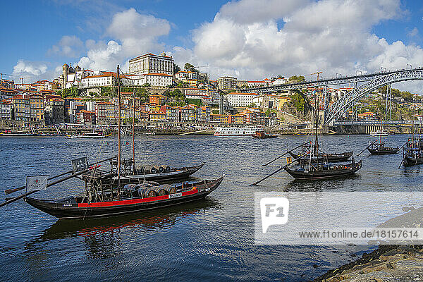 Blick auf die Brücke Dom Luis I. über den Fluss Douro und die Rabelo-Boote in einer Reihe mit bunten Gebäuden  UNESCO-Weltkulturerbe  Porto  Norte  Portugal  Europa