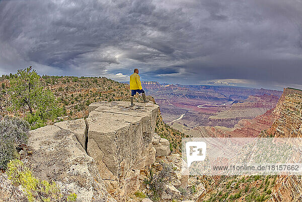 A hiker standing on a cliff between Zuni and Papago Points at Grand Canyon on a stormy day  Grand Canyon National Park  UNESCO World Heritage Site  Arizona  United States of America  North America
