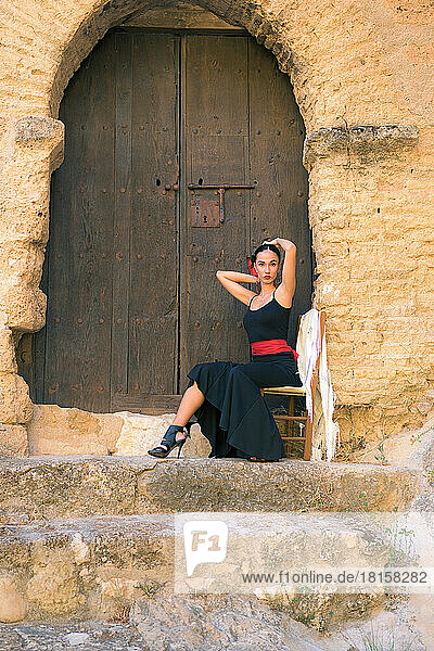 Frau in einem Flamenco-Kostüm vor einem Schlosstor sitzend