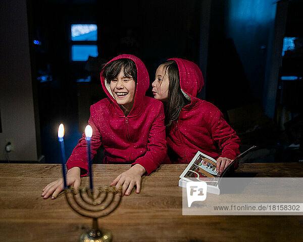 Zwei glückliche Kinder sitzen am Tisch mit Hannukah-Kerzen