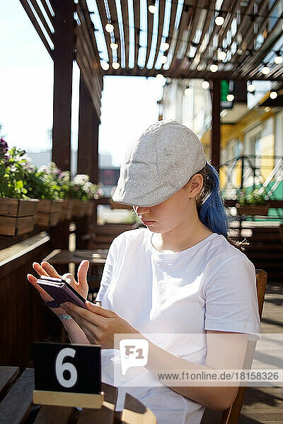 Ein Teenager mit blauen Haaren wartet in einem Café auf eine Bestellung
