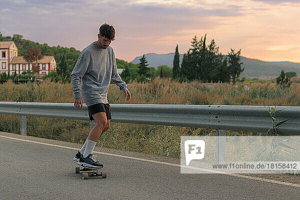 Young man riding a skateboard on the road