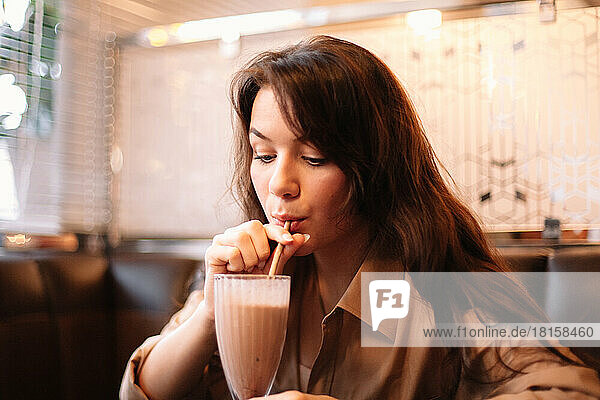 Junge Frau trinkt Schokoladenmilchshake im Restaurant