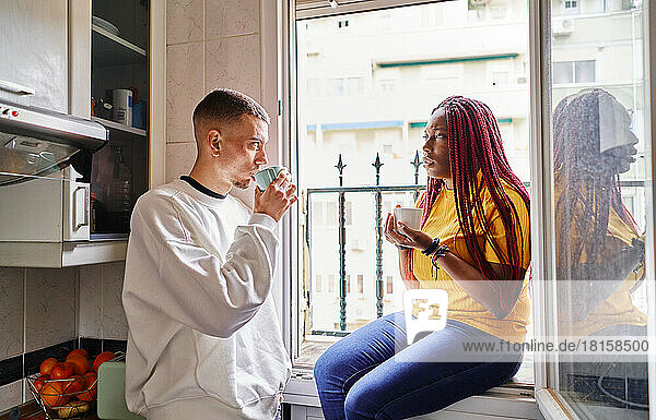 Glückliches multiethnisches Paar beim Kaffee trinken zu Hause
