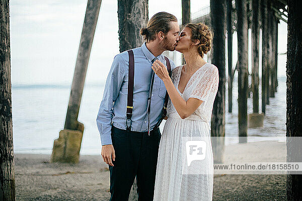 Ein frisch verheiratetes Paar küsst sich am Strand in den Redwoods  Kalifornien