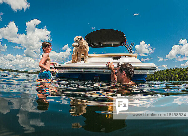 Mann und Kind schwimmen an einem Sommertag von der Rückseite eines Bootes.
