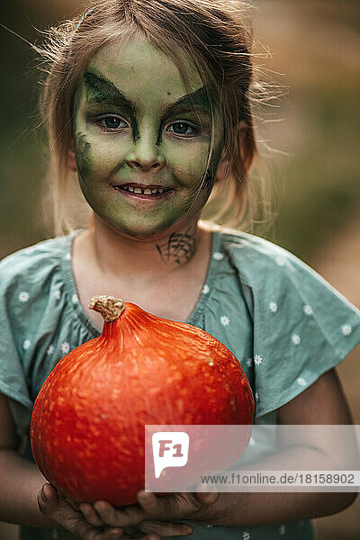 Kleines Mädchen mit Hexe Make-up Halloween-Party mit einem Kürbis