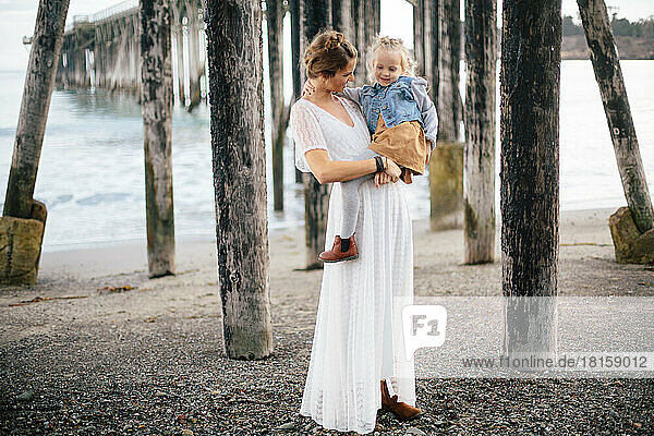 Braut und Tochter posieren während einer Flucht am Strand in Re