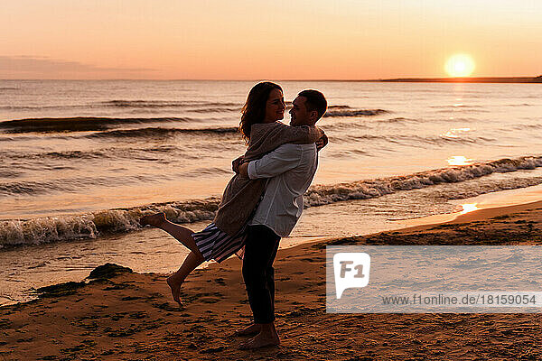 Silhouette eines jungen Liebespaares  das sich am Strand umarmt  während