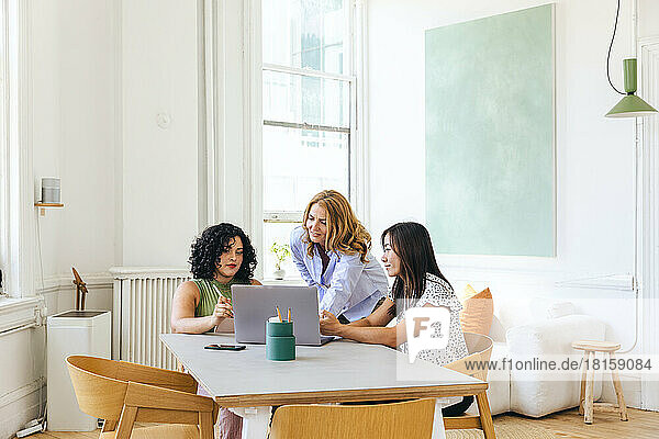 Geschäftsfrau bespricht Strategie mit Kollegen am Laptop