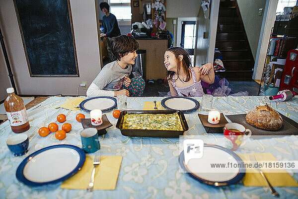 zwei glückliche Kinder setzen sich zu Hause an den Frühstückstisch