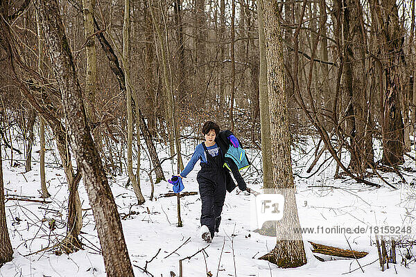 Ein Junge in Schneeausrüstung wandert im Winter durch den Wald