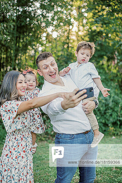 Multiracial family with two kids takes selfie on mobile phone.