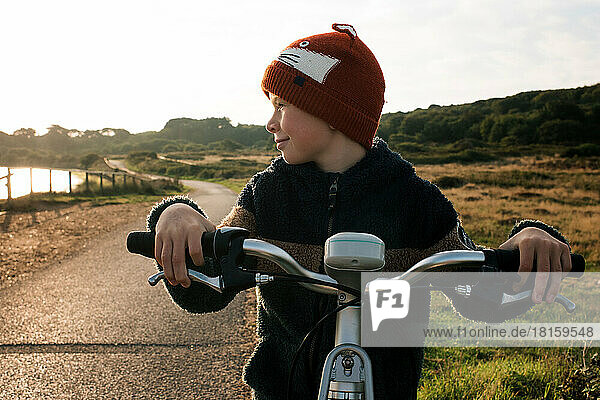 boy looking at the sunrise on a hire bike by the beach