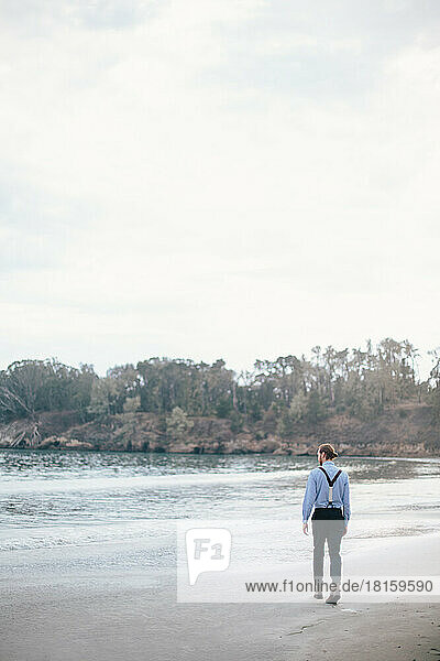 Man in formal wear and man bun walking on beach in Redwoods  Cal