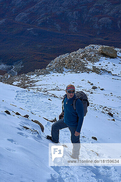 man alone climbing a snowy mountain in patagonia argentina
