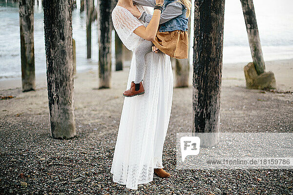 Braut und Tochter posieren während einer Flucht am Strand in Re