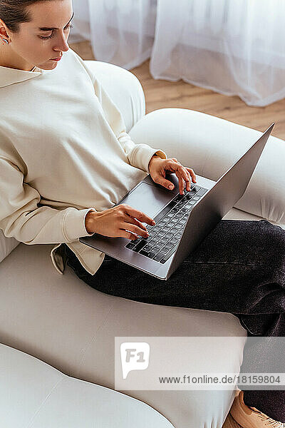 Ein junges Mädchen arbeitet ferngesteuert an einem Laptop in einer hellen Wohnung si
