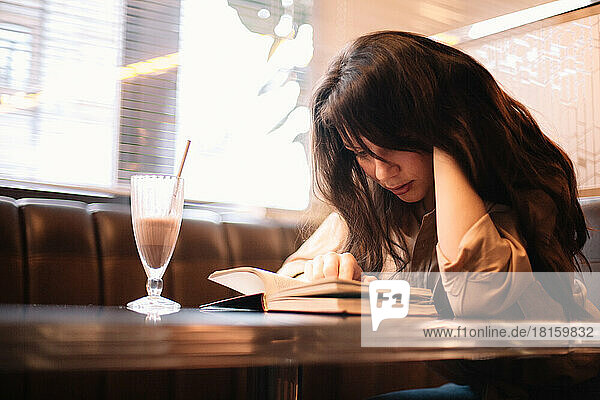 Junge Frau  die in einem Café sitzt und ein Buch liest