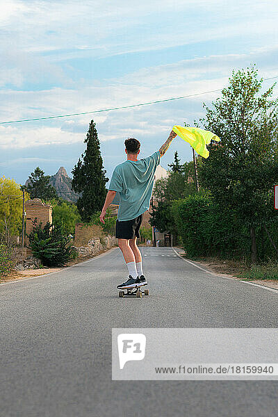 Junger Mann auf einem Skateboard auf einer Straße mit einem reflektierenden Kleidungsstück