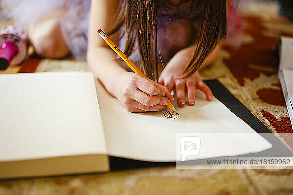 Close-up of child drawing carefully with pencil in sketchbook