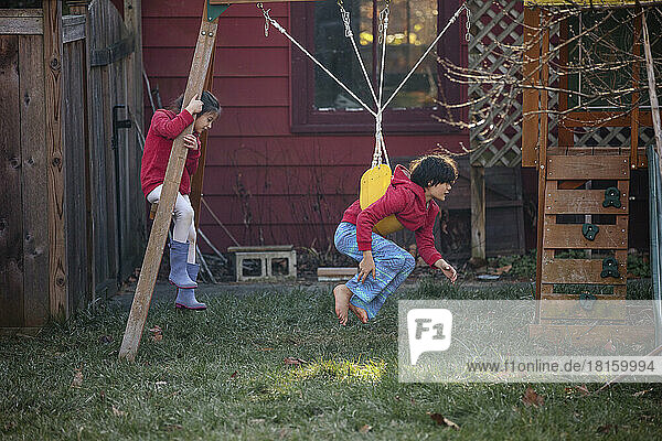 zwei Kinder spielen im Frühling zusammen auf einem Spielplatz im Garten