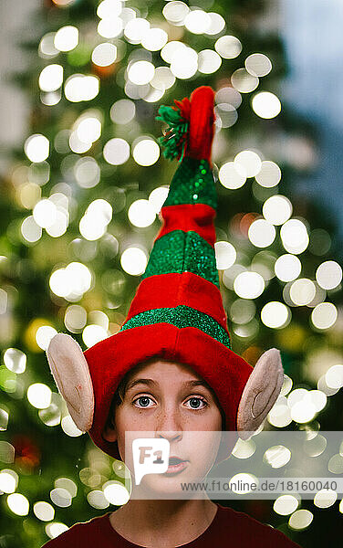Preteen Junge in Weihnachten Elf Hut mit Weihnachtsbaum Licht Bokeh