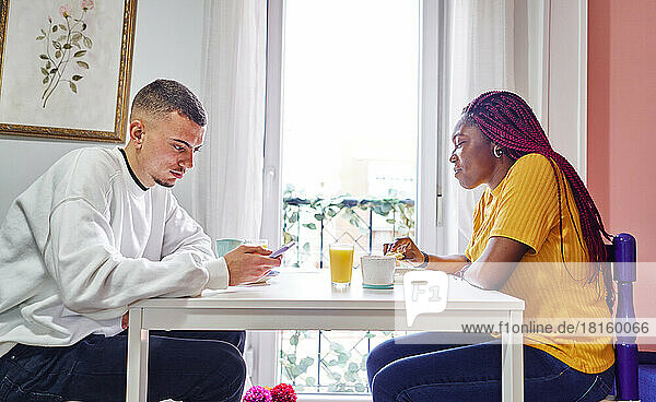 Happy multi-ethnic couple enjoying breakfast at home